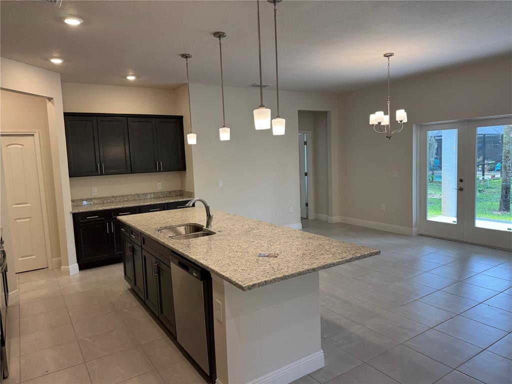 A kitchen with dark cabinets, granite countertops, a center island, and a dining area — 3271 NADASKY AVENUE, NORTH PORT, FL