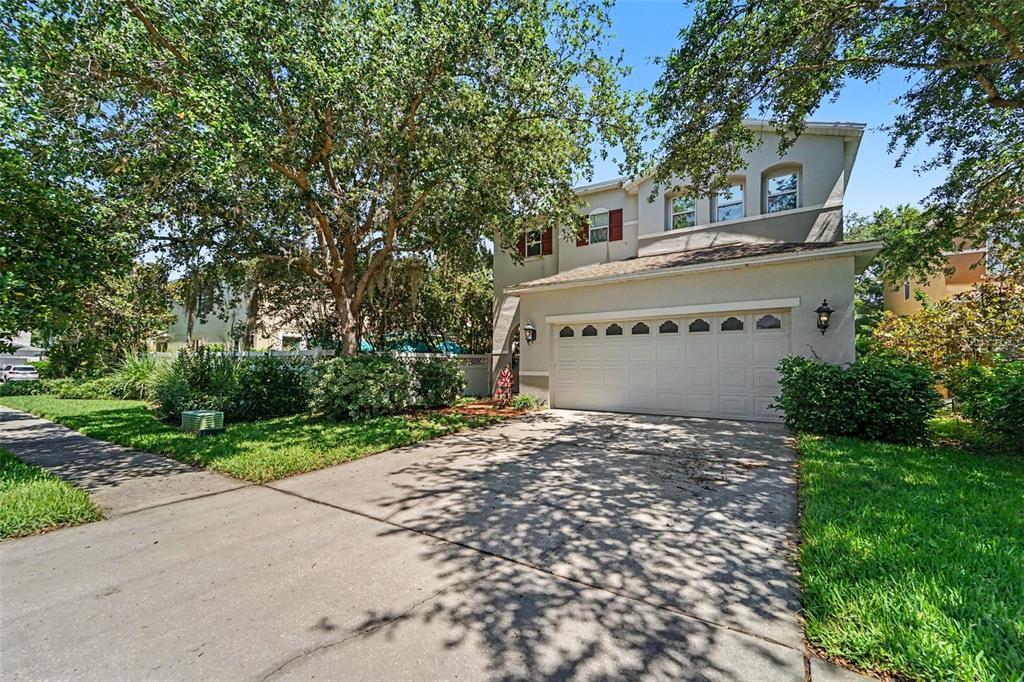 A two-story house with a white garage door, beige siding, and a concrete driveway — 2436 SPRING HOLLOW LOOP, WESLEY CHAPEL, FL