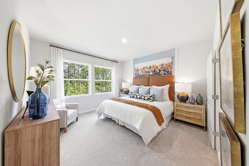 A bedroom features a king bed, a blue accent wall, and a view of trees — 1144 WILD CREST LANE, DAYTONA BEACH, FL