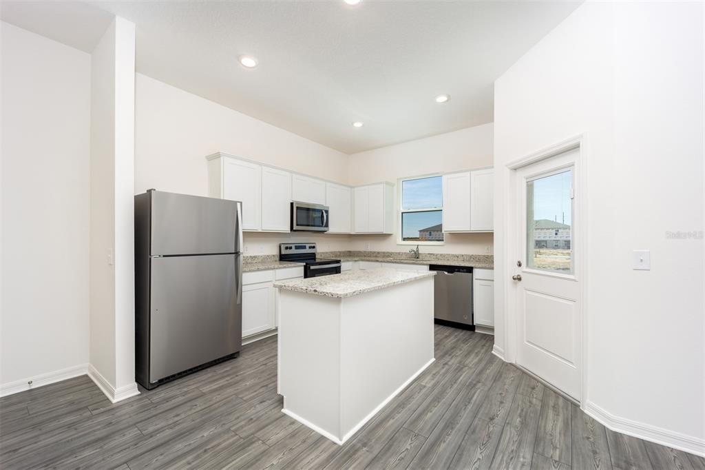 A kitchen features white cabinets, granite countertops, stainless steel appliances, and a central island — 654 POPPY LANE, DUNDEE, FL