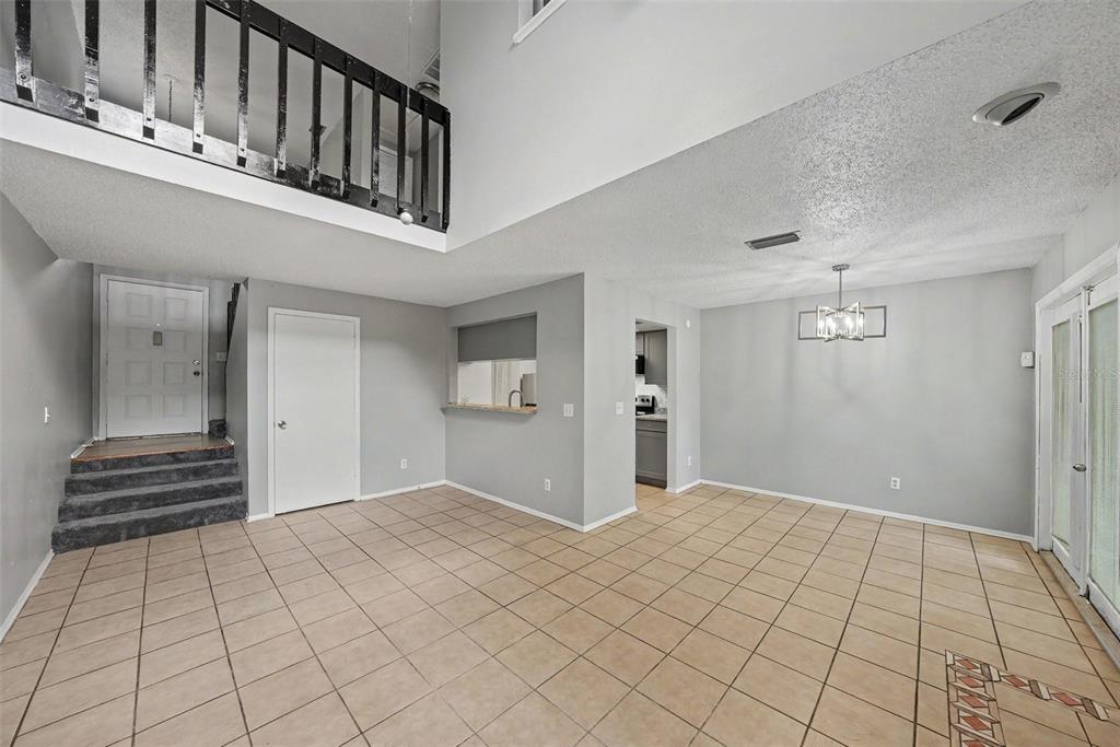 A dining area with tile flooring, a chandelier, and a view of a kitchen pass-through — 12409 TITUS CT, TAMPA, FL