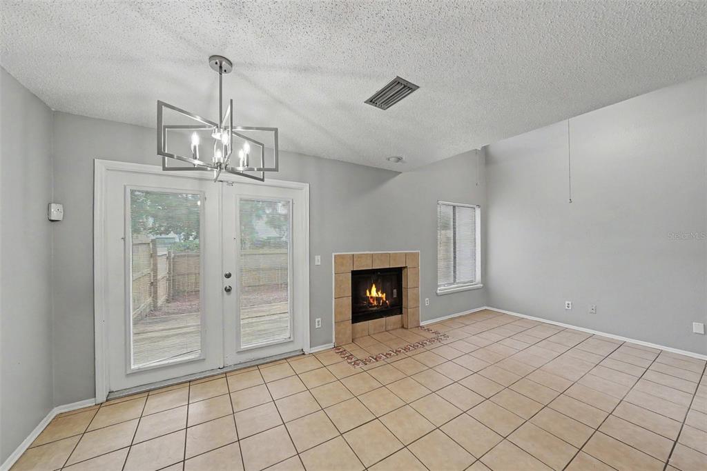A living room with tile flooring, a fireplace, and glass doors leading to a deck — 12409 TITUS CT, TAMPA, FL