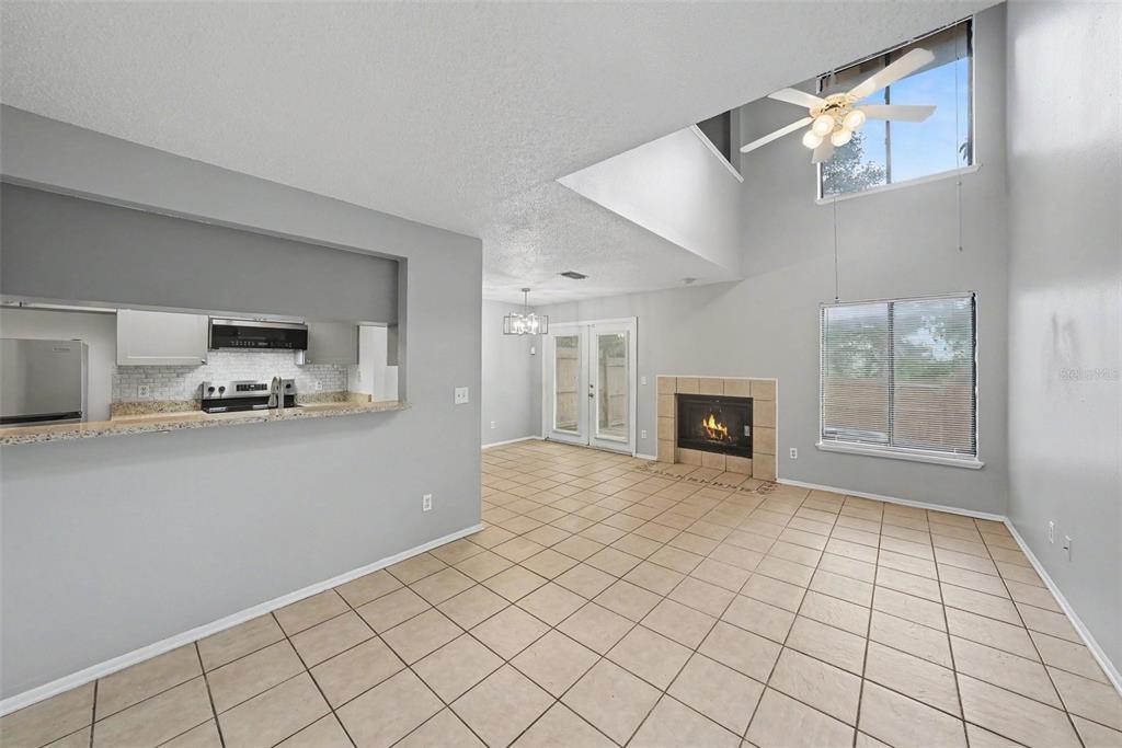 An open-concept living and dining area features tile flooring, a fireplace, and a vaulted ceiling — 12409 TITUS CT, TAMPA, FL