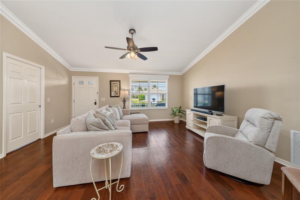 A living room features a sectional sofa, a recliner, a television, and dark wood flooring — 854 FENWICK LOOP, THE VILLAGES, FL