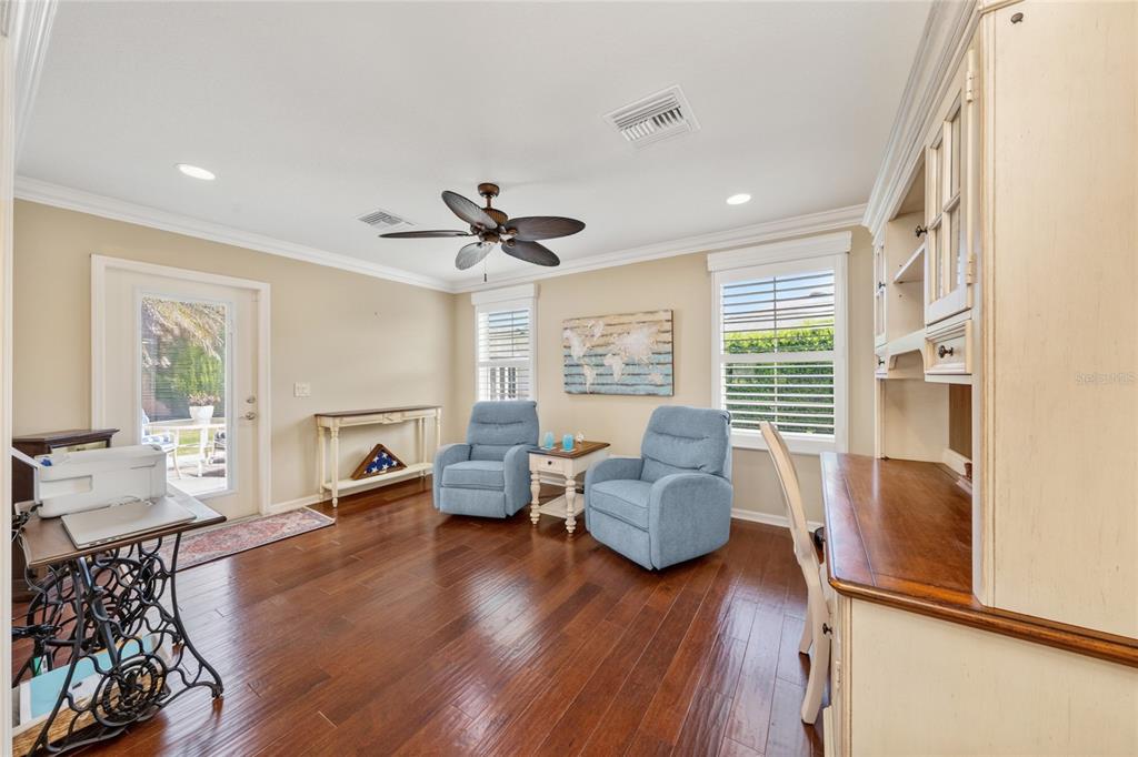 A room with hardwood floors, two blue armchairs, a desk, and a glass-paneled door — 854 FENWICK LOOP, THE VILLAGES, FL