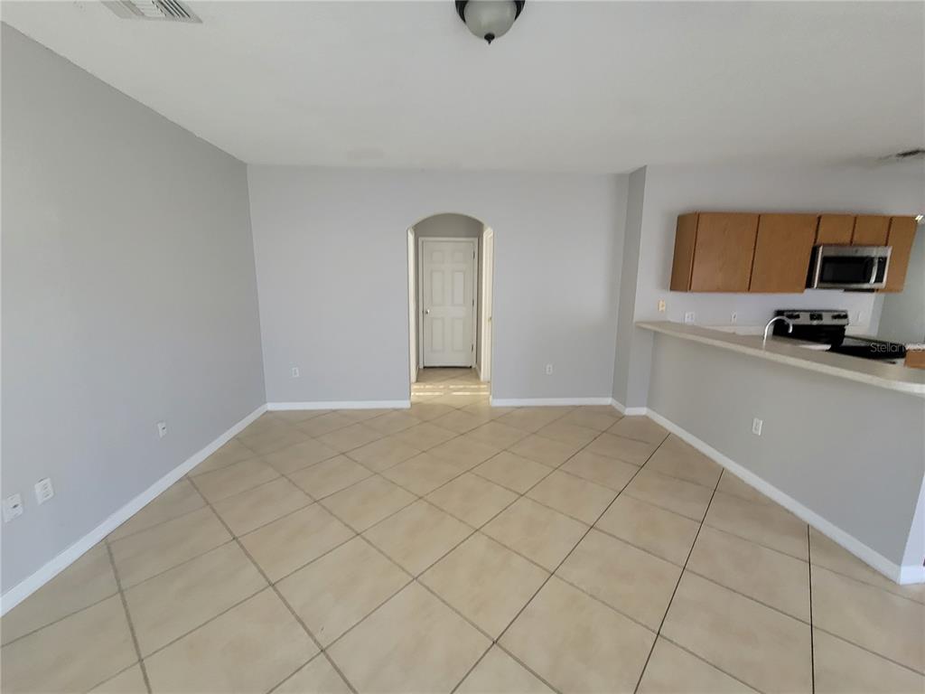 An empty room with light gray walls, tile flooring, and an arched doorway — 319 ALEGRIANO COURT, KISSIMMEE, FL