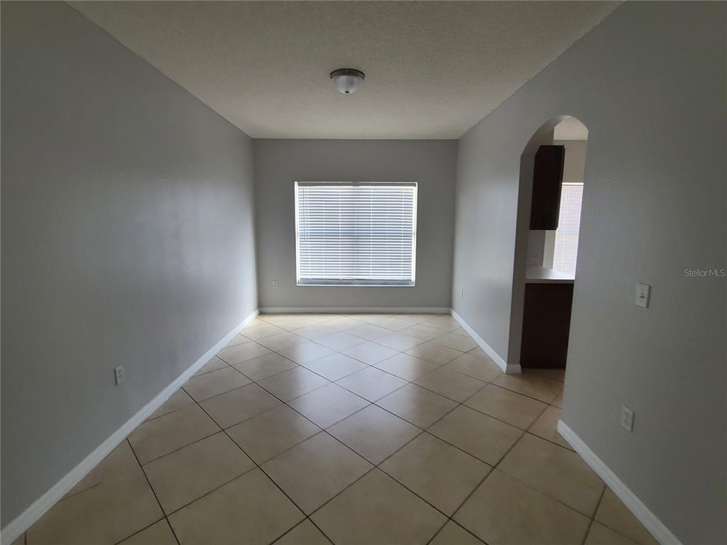 An empty room with light gray walls, tile flooring, and a window with blinds — 319 ALEGRIANO COURT, KISSIMMEE, FL