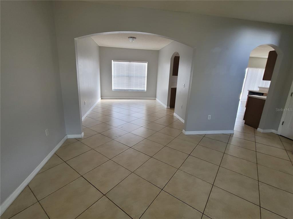 A tiled room features an arched entryway leading to a dining area with a window — 319 ALEGRIANO COURT, KISSIMMEE, FL