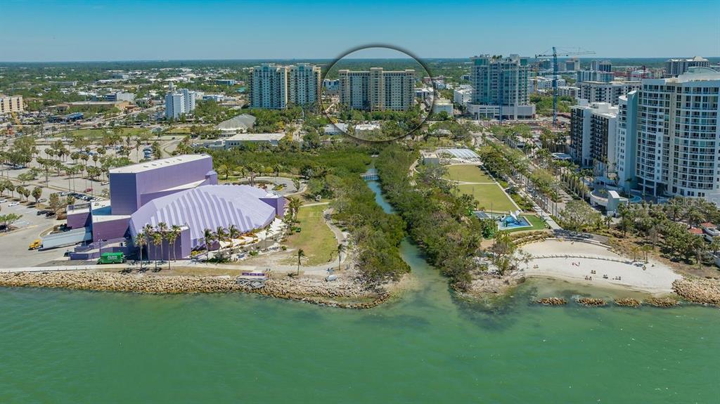 An aerial view shows a coastal park with a large purple building and high-rise condominiums — 750 N TAMIAMI TRAIL UNIT PH08, SARASOTA, FL
