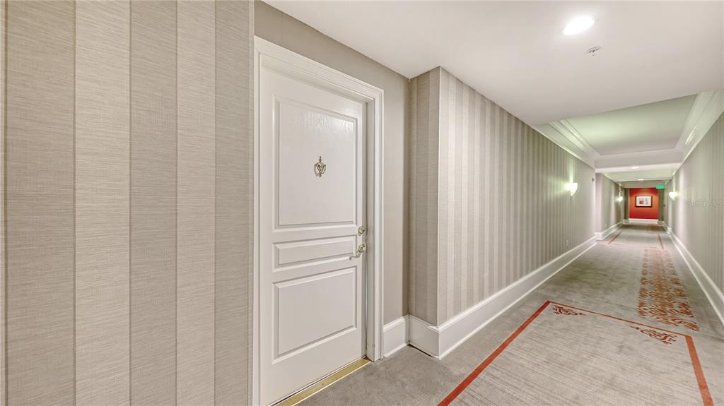 A hallway with striped wallpaper, a white door, and a patterned carpet runner — 750 N TAMIAMI TRAIL UNIT PH08, SARASOTA, FL