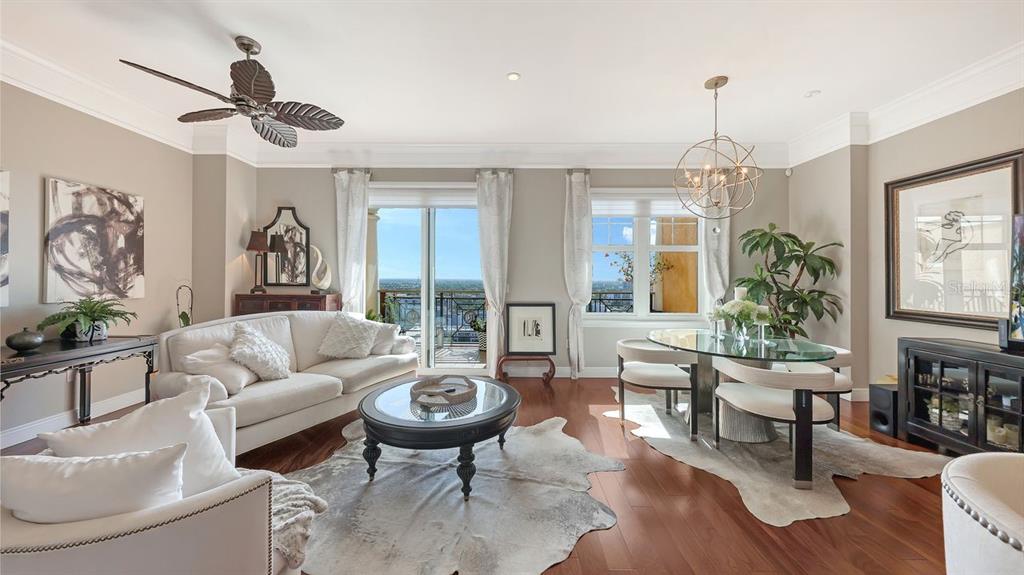 A living and dining room features hardwood floors, a ceiling fan, and a balcony view — 750 N TAMIAMI TRAIL UNIT PH08, SARASOTA, FL