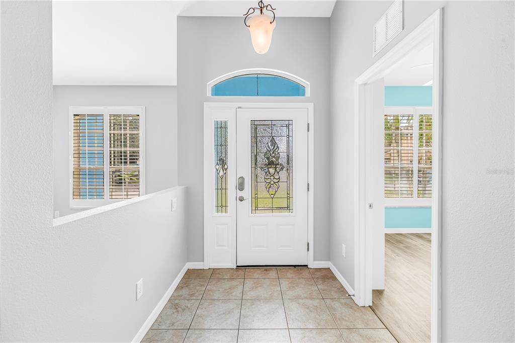 An entryway with tiled flooring, a decorative glass front door, and a light fixture — 6060 97TH AVENUE N, PINELLAS PARK, FL