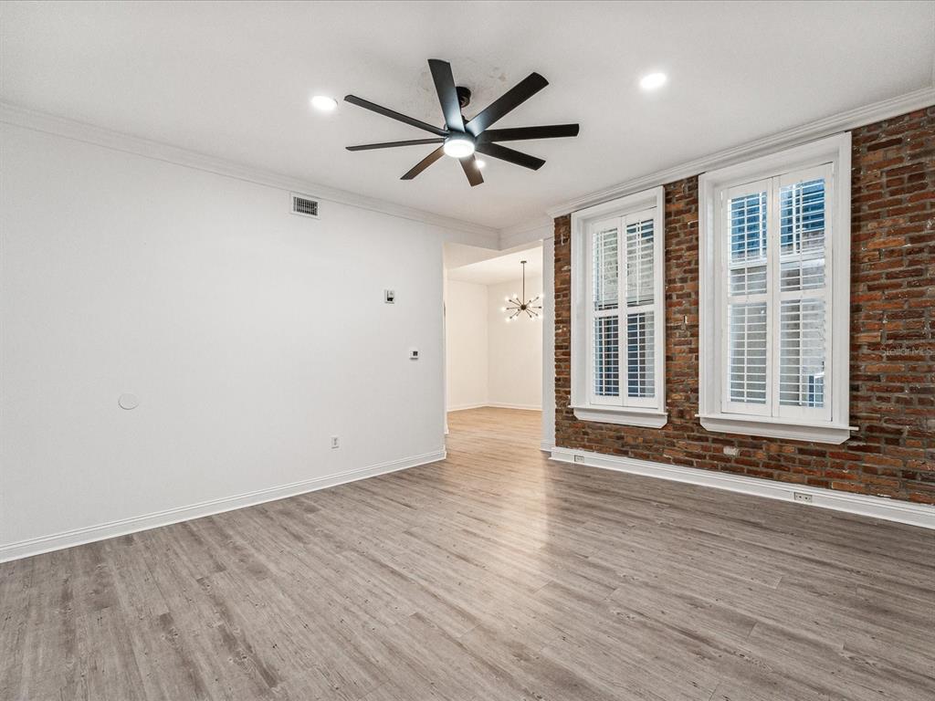 A room with light wood floors, white walls, a ceiling fan, and exposed brick walls — 215 CENTRAL AVENUE UNIT 3F, ST PETERSBURG, FL