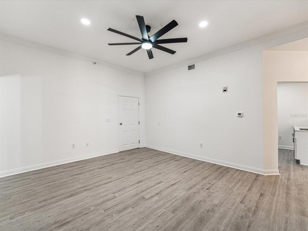 An empty room with white walls, gray wood-look flooring, and a black ceiling fan — 215 CENTRAL AVENUE UNIT 3F, ST PETERSBURG, FL
