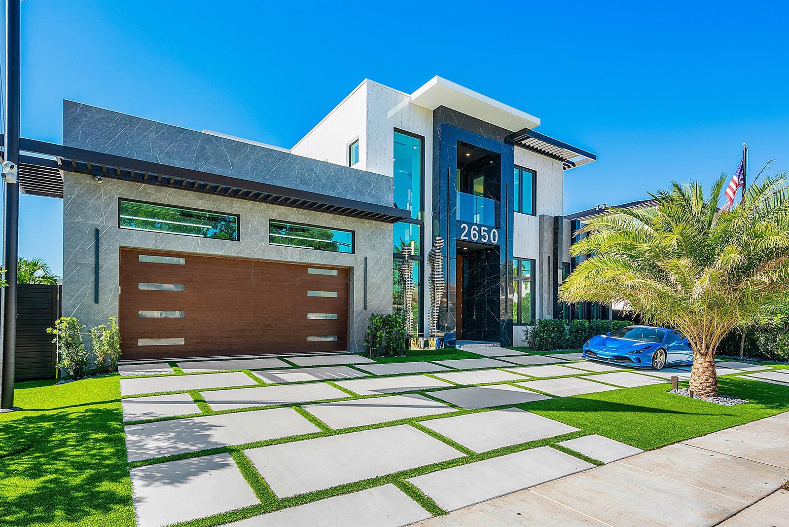 A modern two-story house with a stone facade, a wooden garage door, and a blue car — 2650 NE 48th Court, Lighthouse Point FL 33064, LIGHTHOUSE POINT, FL