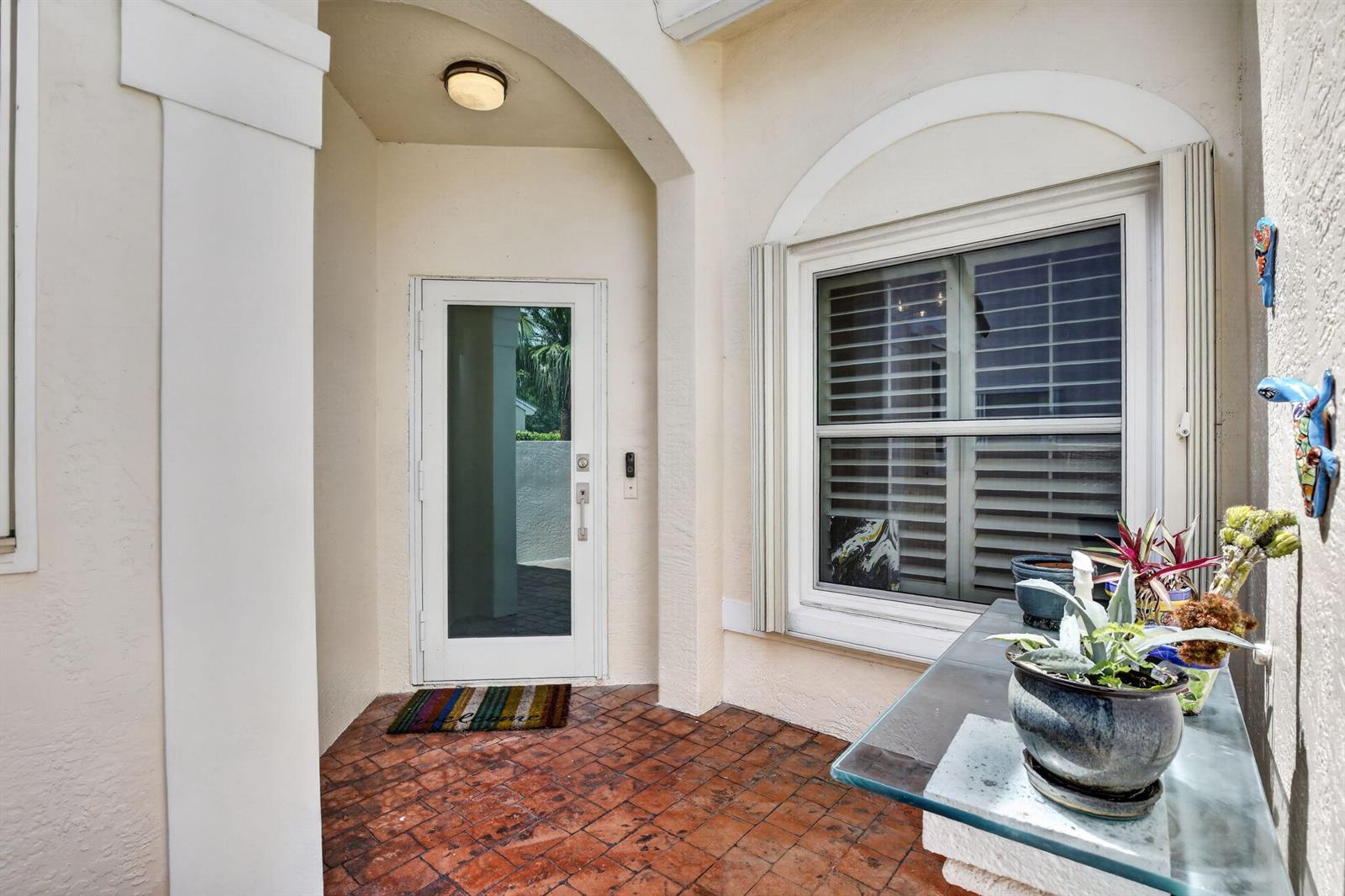 A covered entryway features a white door, a window with shutters, and potted plants — 327 SW 191st Terrace, Pembroke Pines FL 33029, PEMBROKE PINES, FL