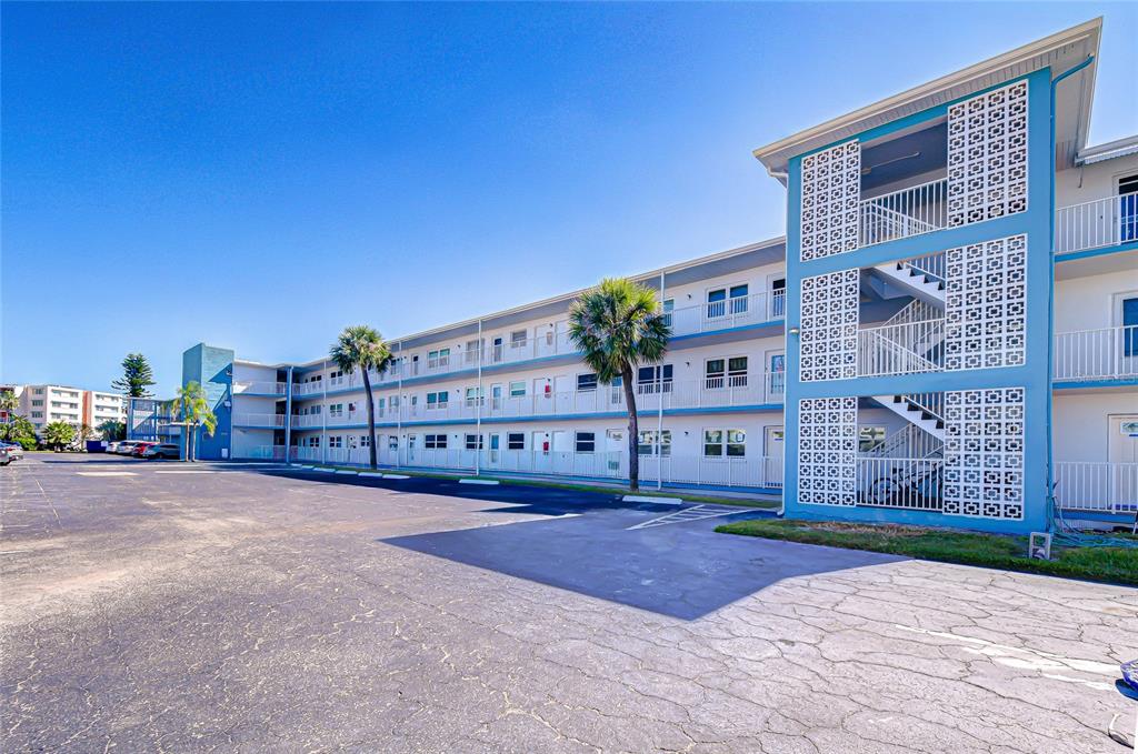 A three-story apartment building with blue exterior accents and an adjacent paved parking lot — 1893 SHORE DRIVE S UNIT 206, SOUTH PASADENA, FL
