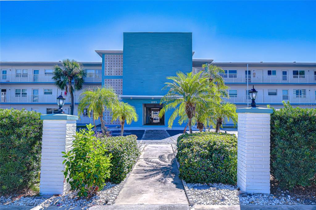 A blue multi-story apartment building features a central entrance walkway flanked by two white pillars — 1893 SHORE DRIVE S UNIT 206, SOUTH PASADENA, FL
