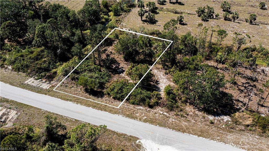 An aerial view shows a vacant, wooded lot outlined in white next to a paved road — 12533 GREEN GULF BOULEVARD, PUNTA GORDA, FL