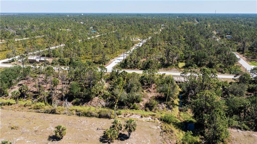 An aerial view shows a vacant, wooded residential lot outlined in yellow near a paved road — 12533 GREEN GULF BOULEVARD, PUNTA GORDA, FL