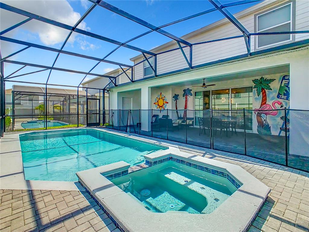 A screened-in patio features a swimming pool, a hot tub, and a mural on the wall — 1978 SUMMER DRIVE, DAVENPORT, FL