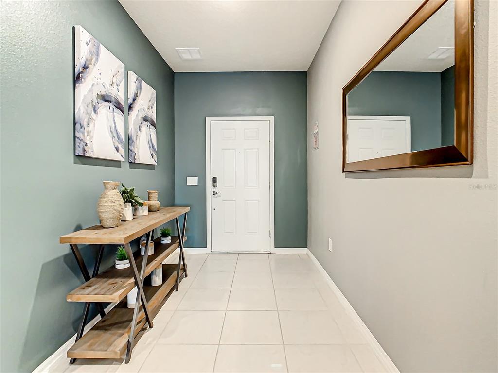 An entryway features a console table, wall art, a large mirror, and tiled flooring — 1978 SUMMER DRIVE, DAVENPORT, FL