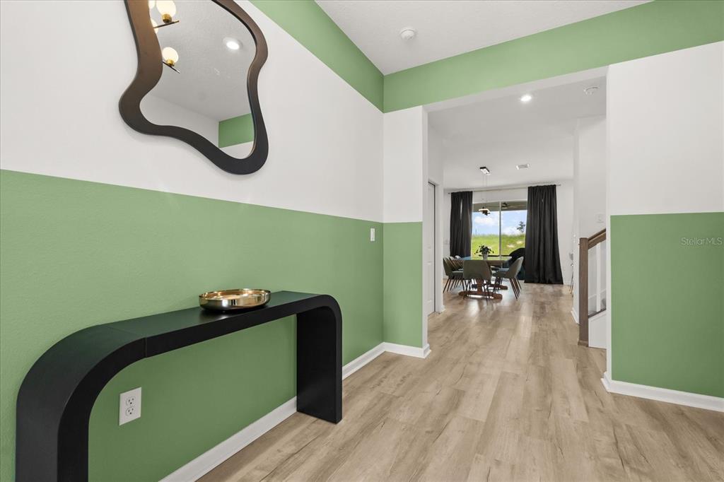 An entryway with green and white walls, a black console table, and a mirror — 9098 BEACH TEA WAY, KISSIMMEE, FL