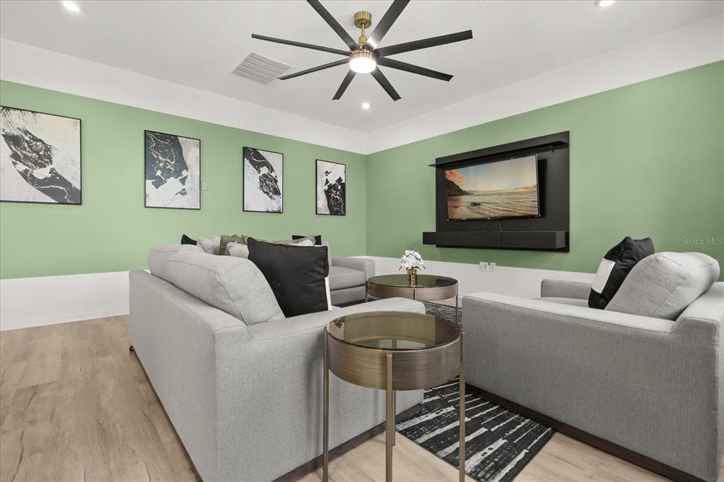 A living room features light green walls, gray sofas, a ceiling fan, and wall art — 9098 BEACH TEA WAY, KISSIMMEE, FL