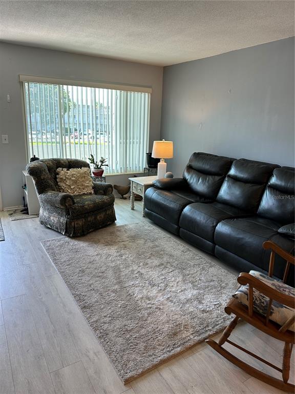A living room features a black leather sofa, a patterned armchair, and a wooden rocking chair — 2448 COLUMBIA DRIVE UNIT 28, CLEARWATER, FL