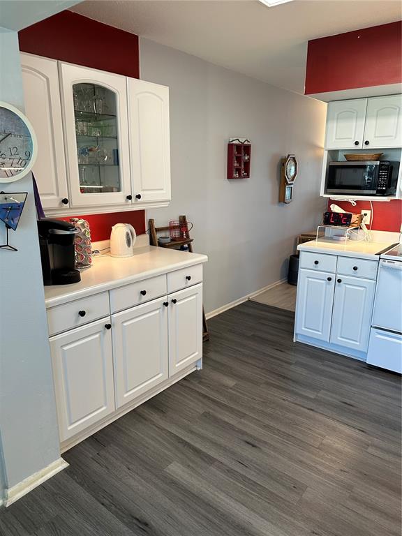 A kitchen features white cabinets, a microwave, a coffee maker, and gray wood-look flooring — 2448 COLUMBIA DRIVE UNIT 28, CLEARWATER, FL