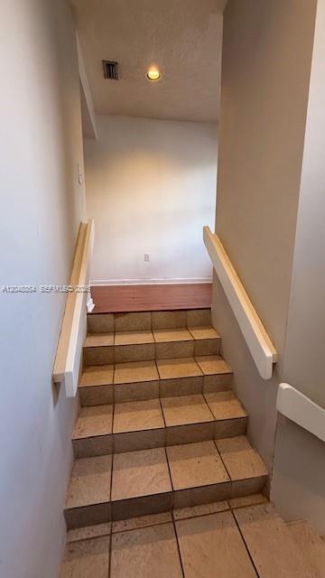 A staircase with beige tiled steps and white handrails leads to an upper level — 9691 SW 138th Ave, Miami FL 33186, MIAMI, FL