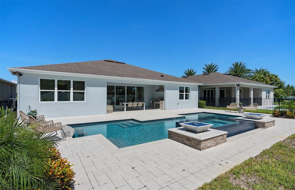 A backyard features a swimming pool with a spa, fire feature, and paved patio area — 6213 CITRUS GROVE COURT, ST CLOUD, FL