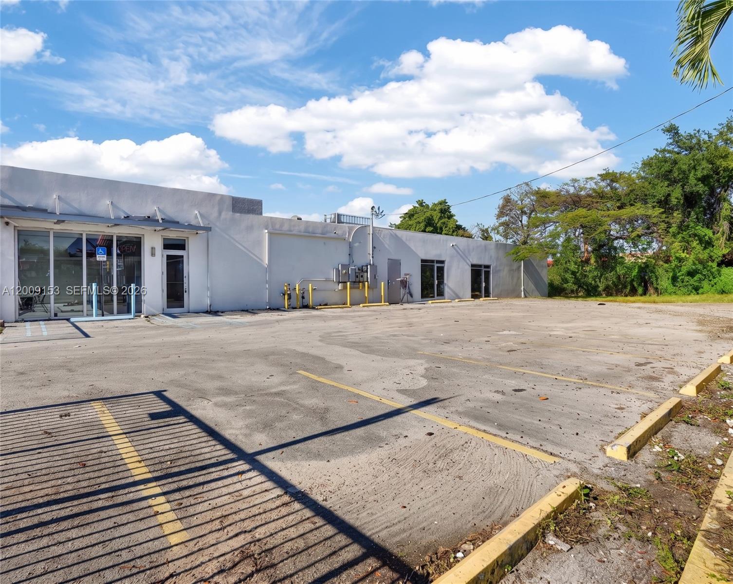A one-story commercial building with a paved parking lot and yellow concrete wheel stops — 69 NW 27th Ave, Miami FL 33125, MIAMI, FL