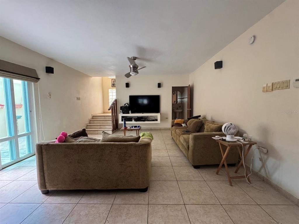 A living room features tile floors, two sofas, a wall-mounted television, and a ceiling fan — 2 B-15 URB. ALTURAS DE MONTE BRISAS, GURABO, PR