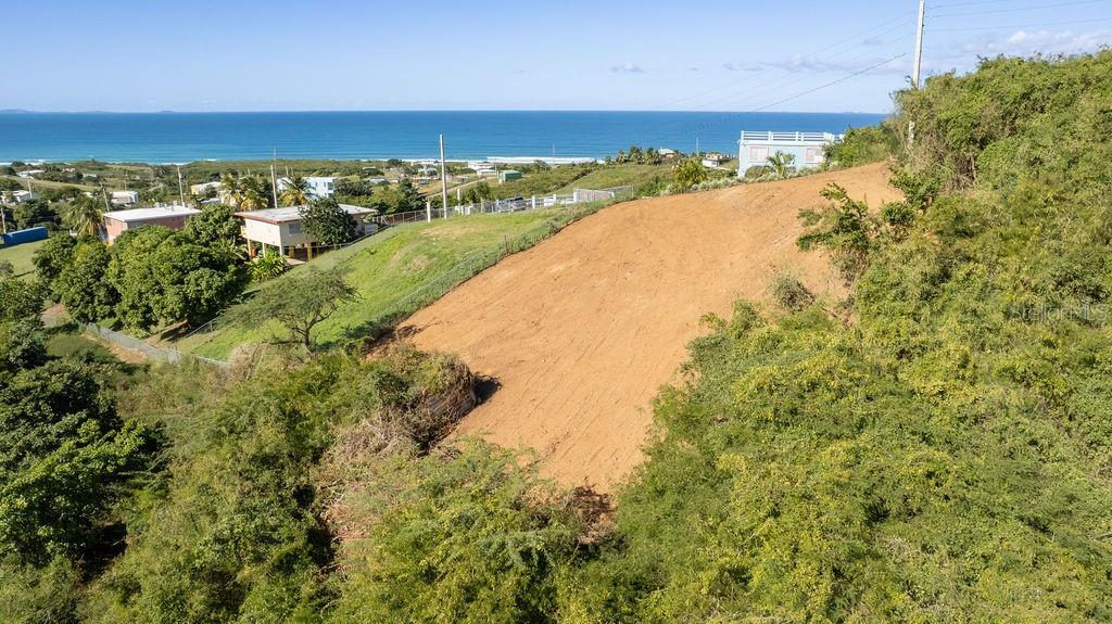 An elevated, sloped, cleared dirt lot overlooks the ocean and nearby houses — 583 CALLE 16, VIEQUES, PR