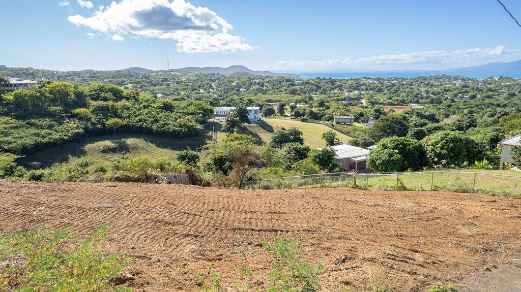 A view of a cleared, sloped dirt lot overlooking a lush valley and the ocean — 583 CALLE 16, VIEQUES, PR