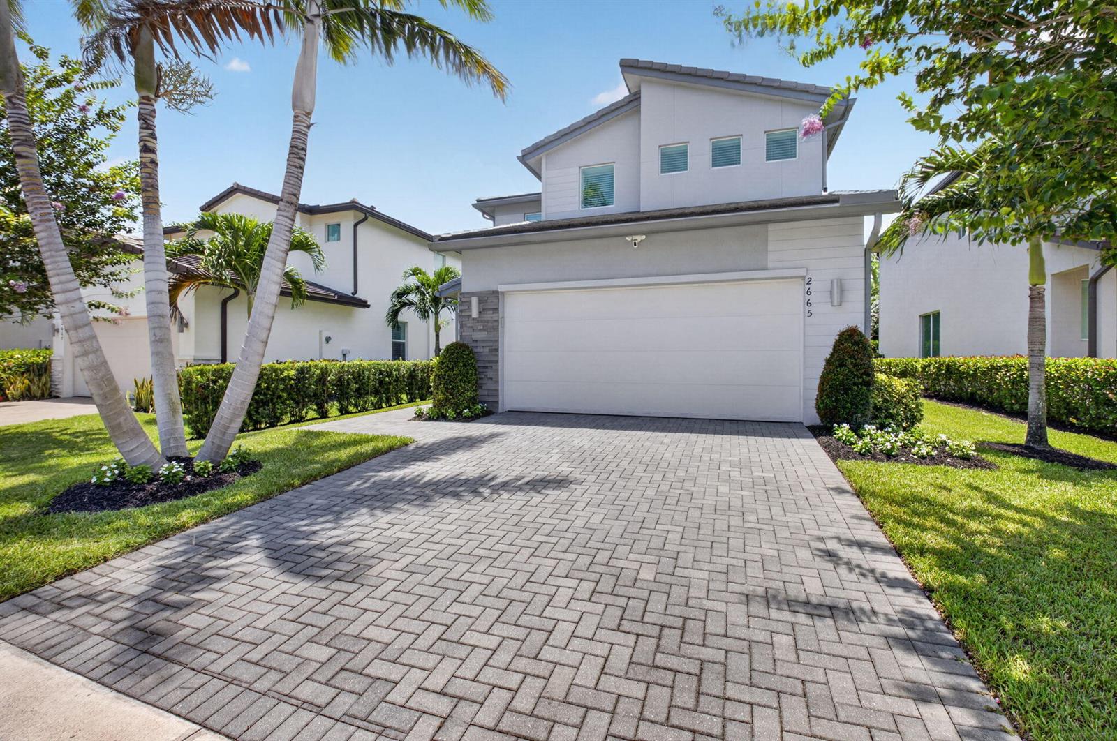 A two-story house with a white garage door, gray stone accents, and a paved driveway — 2665 Country Lake Trail, Boynton Beach FL 33436, BOYNTON BEACH, FL
