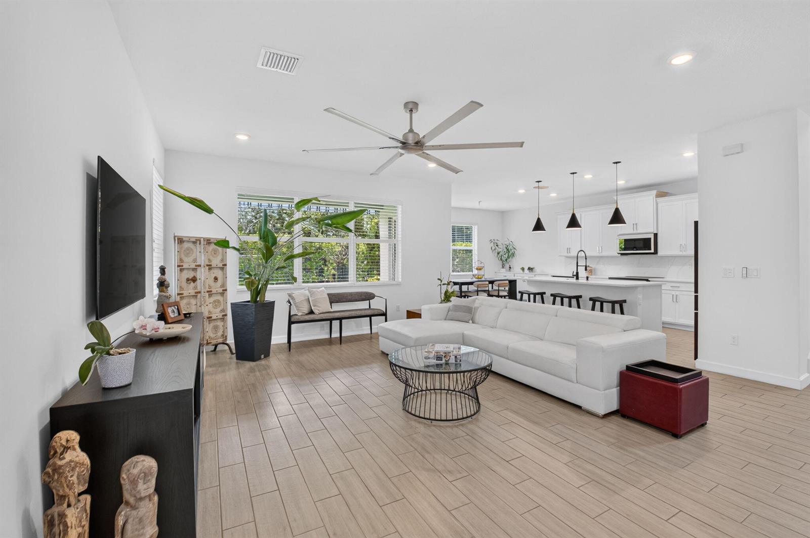 An open-concept living room and kitchen feature white cabinetry, a sectional sofa, and tile flooring — 2665 Country Lake Trail, Boynton Beach FL 33436, BOYNTON BEACH, FL