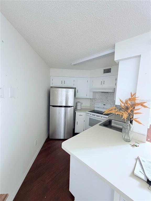 A kitchen features white cabinets, stainless steel appliances, and a peninsula with a sink — 3795 ATRIUM DRIVE UNIT U7, ORLANDO, FL