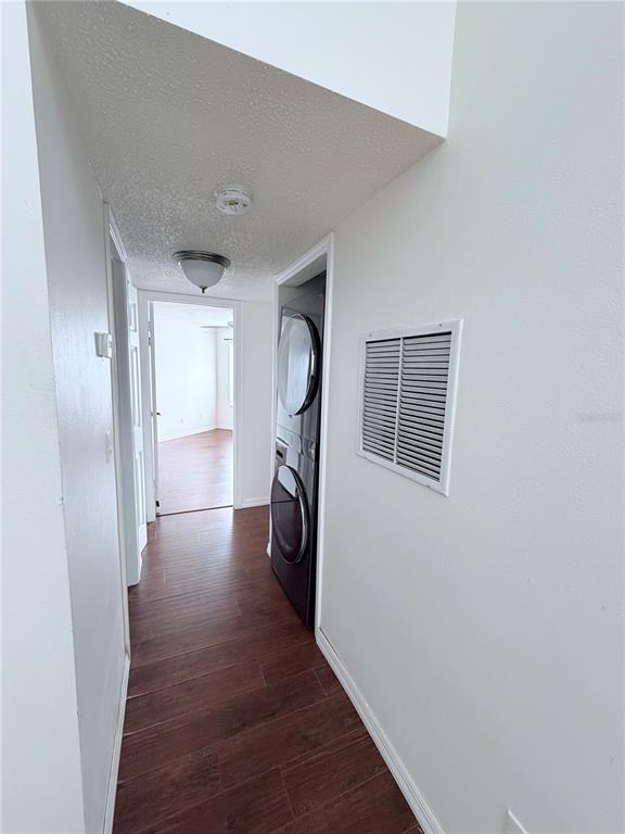 A hallway features wood-look flooring, a ceiling light, and a stacked washer and dryer unit — 3795 ATRIUM DRIVE UNIT U7, ORLANDO, FL
