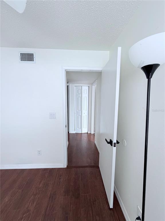 A room with wood-look tile flooring leads through an open doorway into a hallway — 3795 ATRIUM DRIVE UNIT U7, ORLANDO, FL