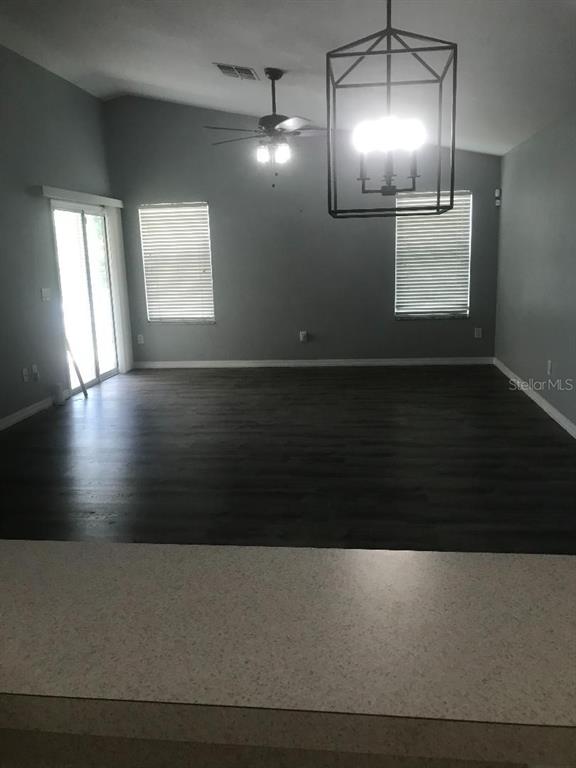 A living room with dark wood-look flooring, a ceiling fan, and a large pendant light — 12377 NE 50TH VIEW, OXFORD, FL