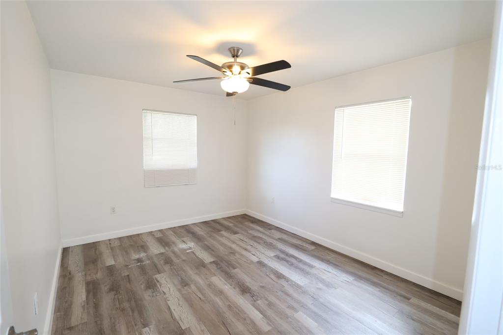 An empty bedroom features white walls, wood-look vinyl flooring, and a ceiling fan — 918 S SCENIC HIGHWAY, LAKE WALES, FL