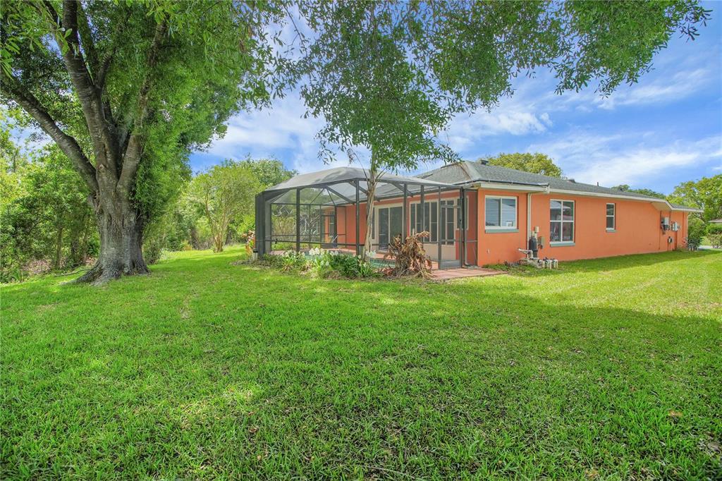 The exterior of an orange house features a screened-in pool enclosure and a large backyard — 333 RANCHWOOD DRIVE, LEESBURG, FL