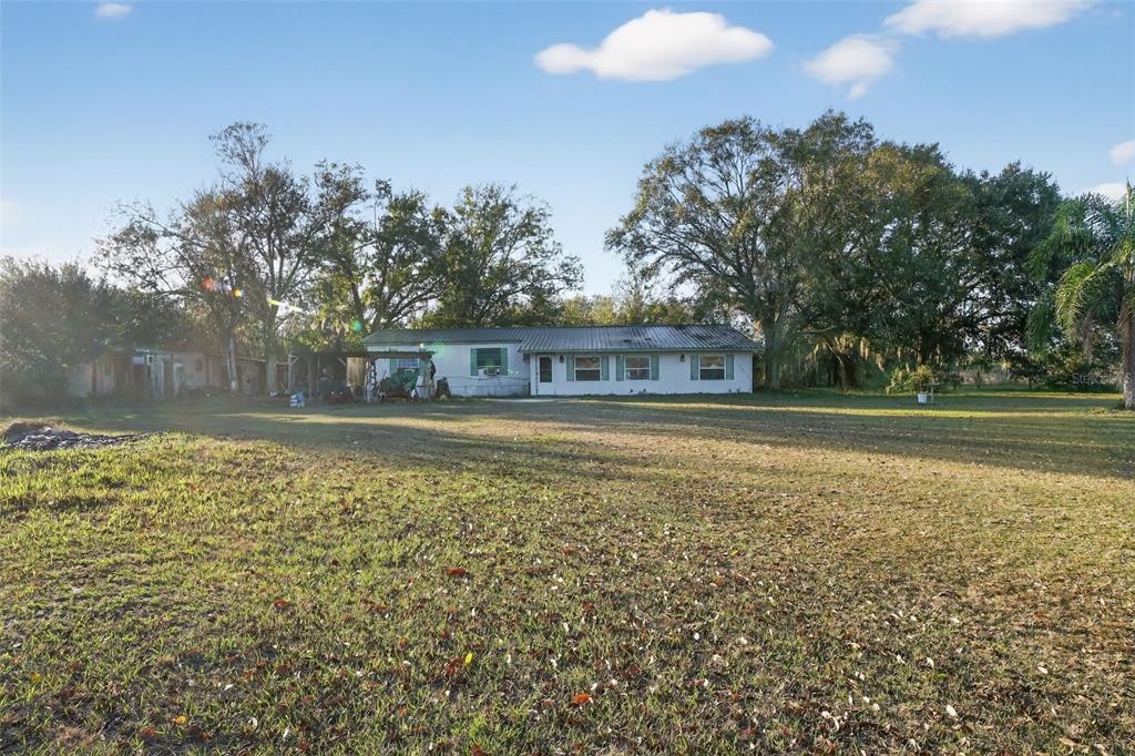 A single-story house with a metal roof sits on a large, grassy lot with trees — 2774 SNIPE DRIVE, ZOLFO SPRINGS, FL
