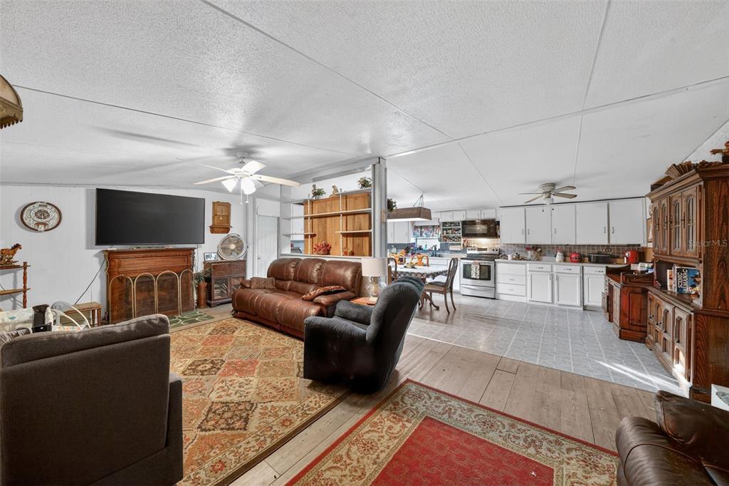 A living room with a brown leather sofa and armchair opens into a white kitchen — 2774 SNIPE DRIVE, ZOLFO SPRINGS, FL