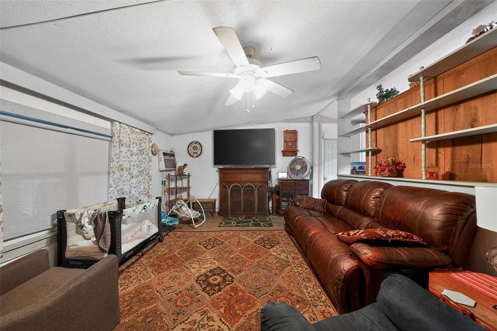 A living room features a leather sofa, a patterned area rug, and a fireplace with television — 2774 SNIPE DRIVE, ZOLFO SPRINGS, FL