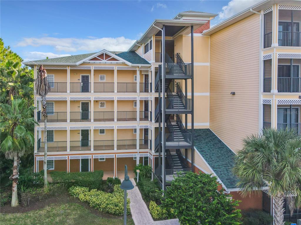 An exterior view of a multi-story apartment building with balconies and an outdoor stairwell — 9061 TREASURE TROVE LANE UNIT 403, KISSIMMEE, FL