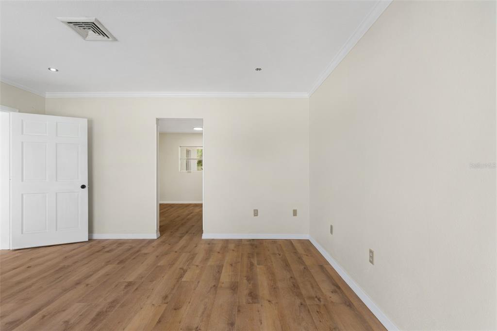 An empty room with light-colored walls, wood-look flooring, and a doorway leading to another space — 1455 COURT STREET, CLEARWATER, FL