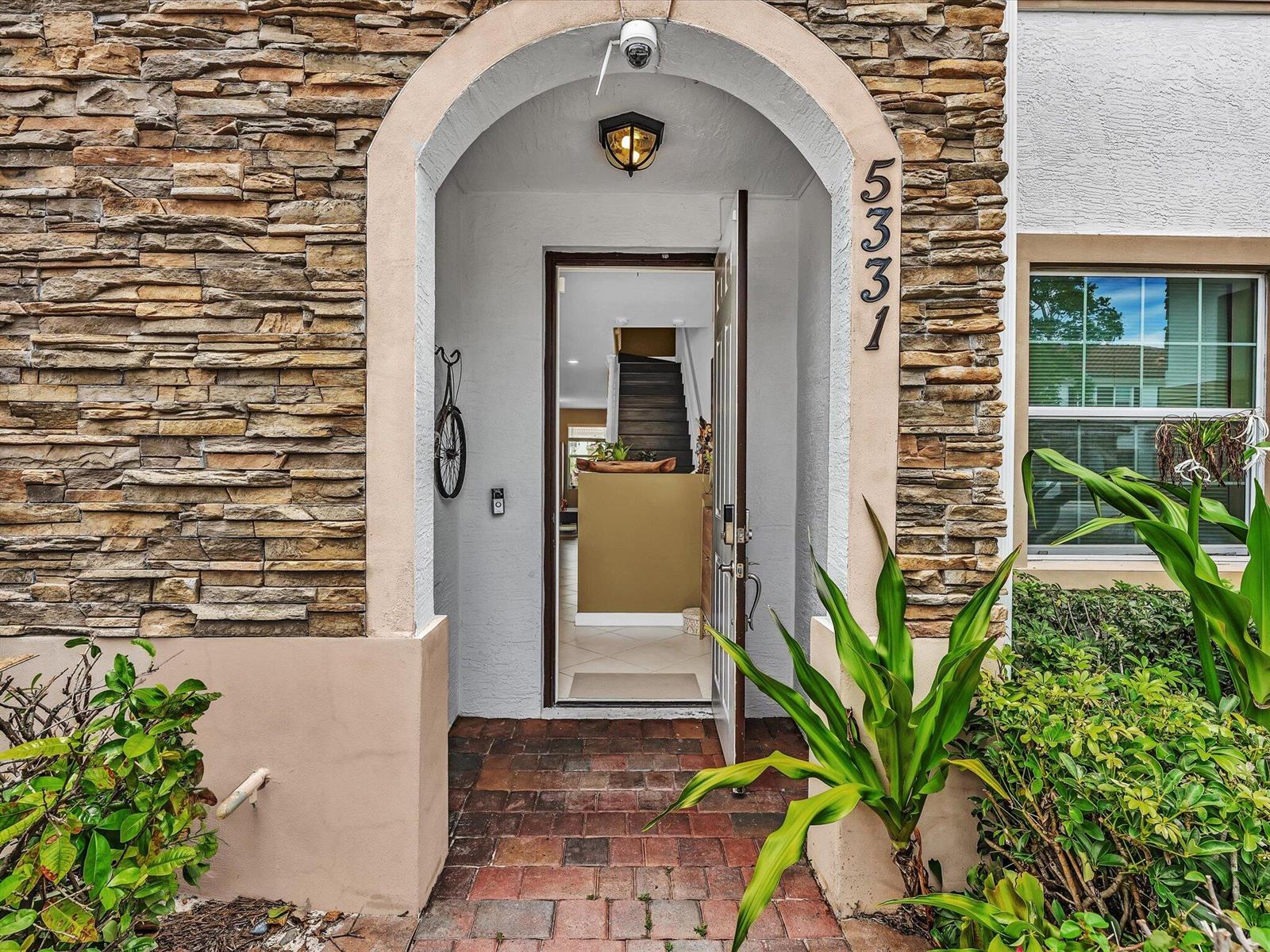 An arched entryway features stone veneer siding, a brick walkway, and an open front door — 5331 Ashley River Road, West Palm Beach FL 33417, WEST PALM BEACH, FL